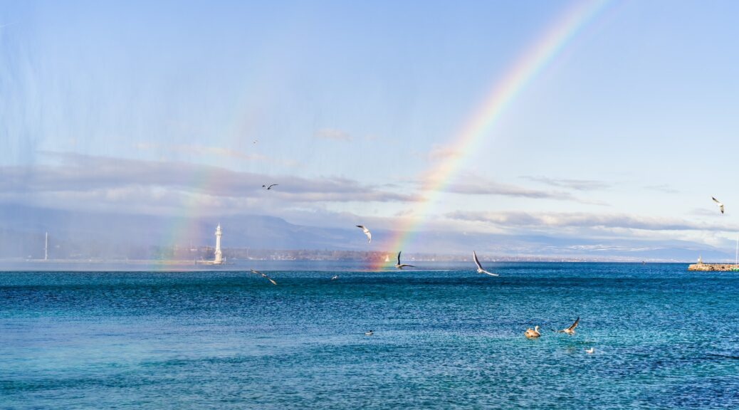 Beautiful double rainbow over blue Lac Léman in Geneva at bright sunny day.