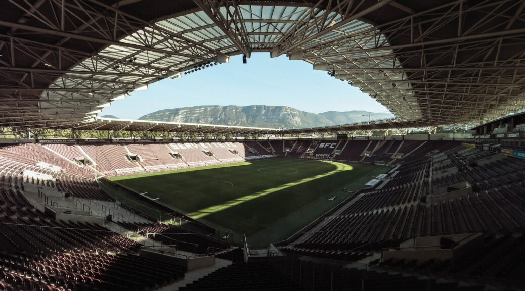 an empty soccer stadium with mountains in the background