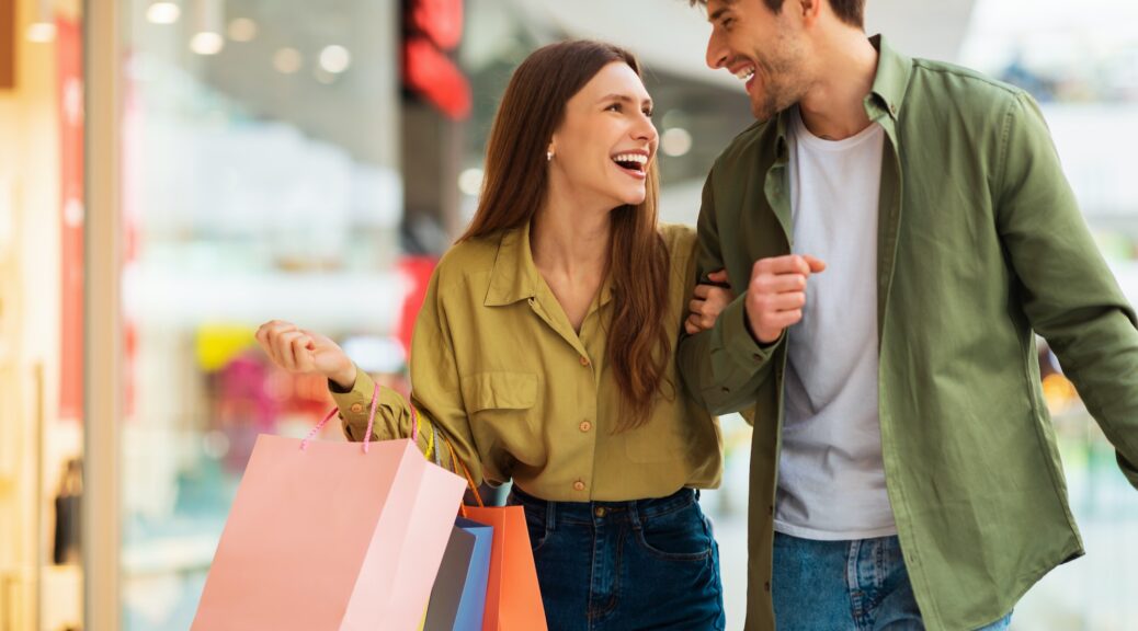 Joyful Couple Carrying Shopping Bags Laughing Spending Time In Mall